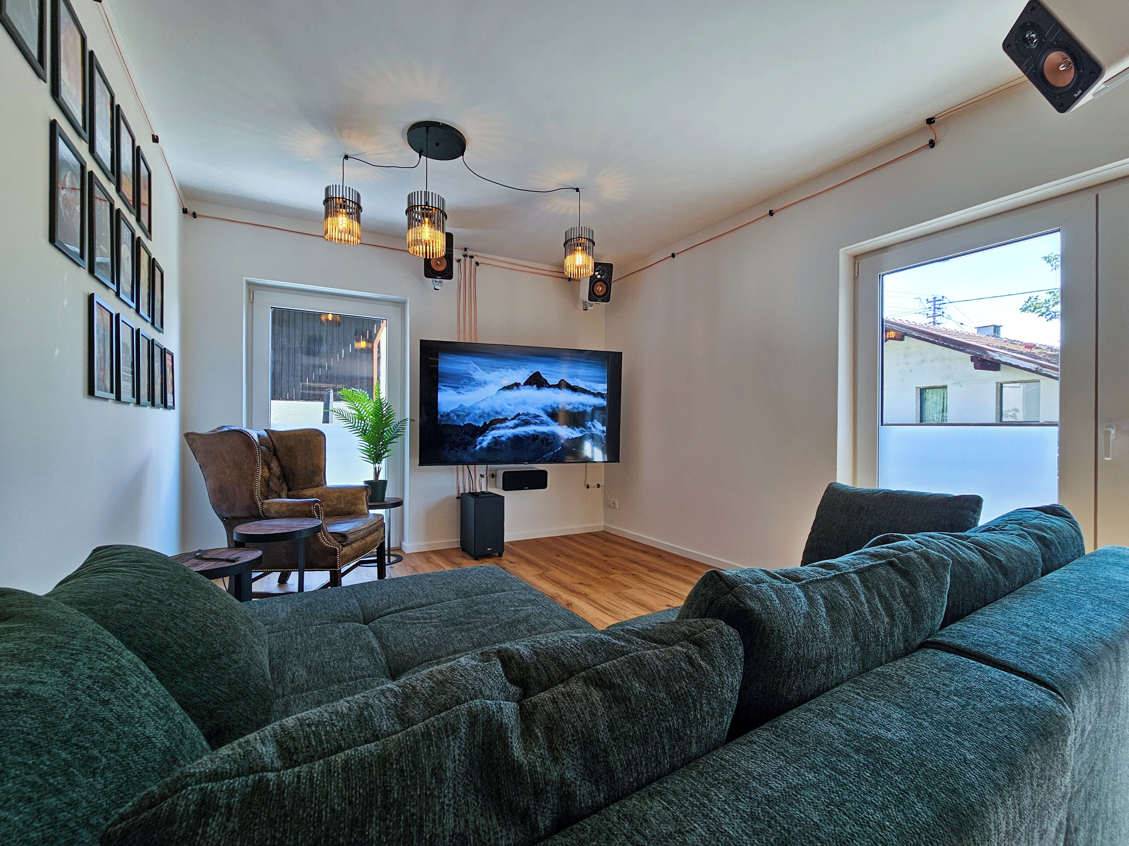 Een moderne woonkamer met een grote flatscreen televisie, een bank, een fauteuil en een plant.