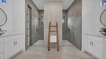 A modern bathroom with a central column, wooden ladder, and white cabinets.