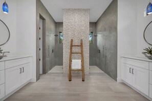 Un baño moderno con una columna central, escalera de madera y armarios blancos.