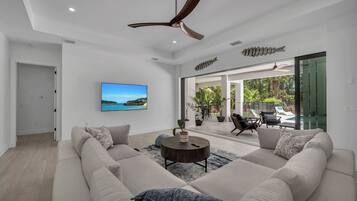 A modern living room with a large sectional sofa, a round coffee table, and a ceiling fan.