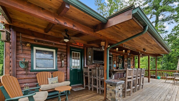 A rustic wooden cabin with a porch, outdoor seating, and a green door.