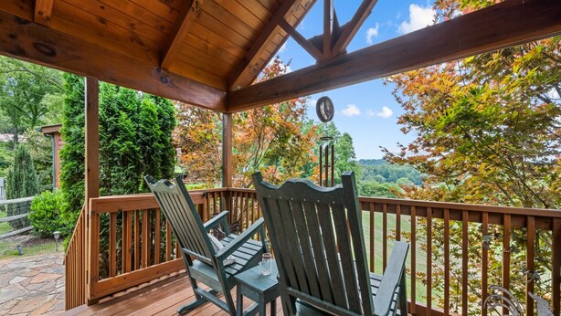 Una terraza de madera con dos sillas Adirondack y una decoración de gallo de metal.