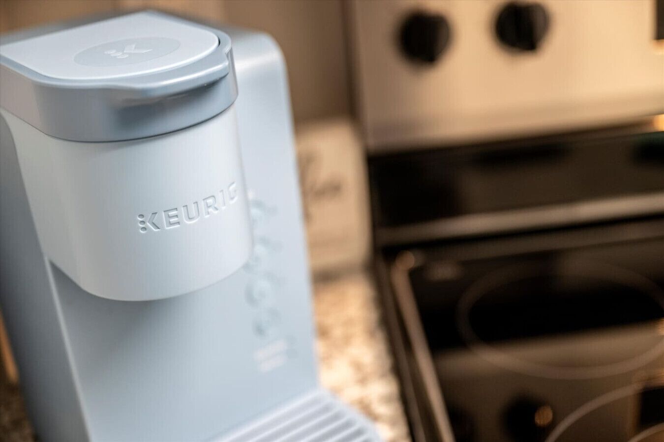 Une cuisine avec un appareil électroménager bleu, peut-être une machine à café, et une cuisinière.
