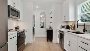 A modern kitchen with white cabinetry, stainless steel appliances, and a wooden floor. - East Lake Escape | Quick Ride to Decatur & Atlanta (Atlanta)
