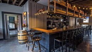 A bar area with a long counter, multiple stools, and a rustic wooden ceiling. - East Lake Escape | Quick Ride to Decatur & Atlanta (Atlanta)