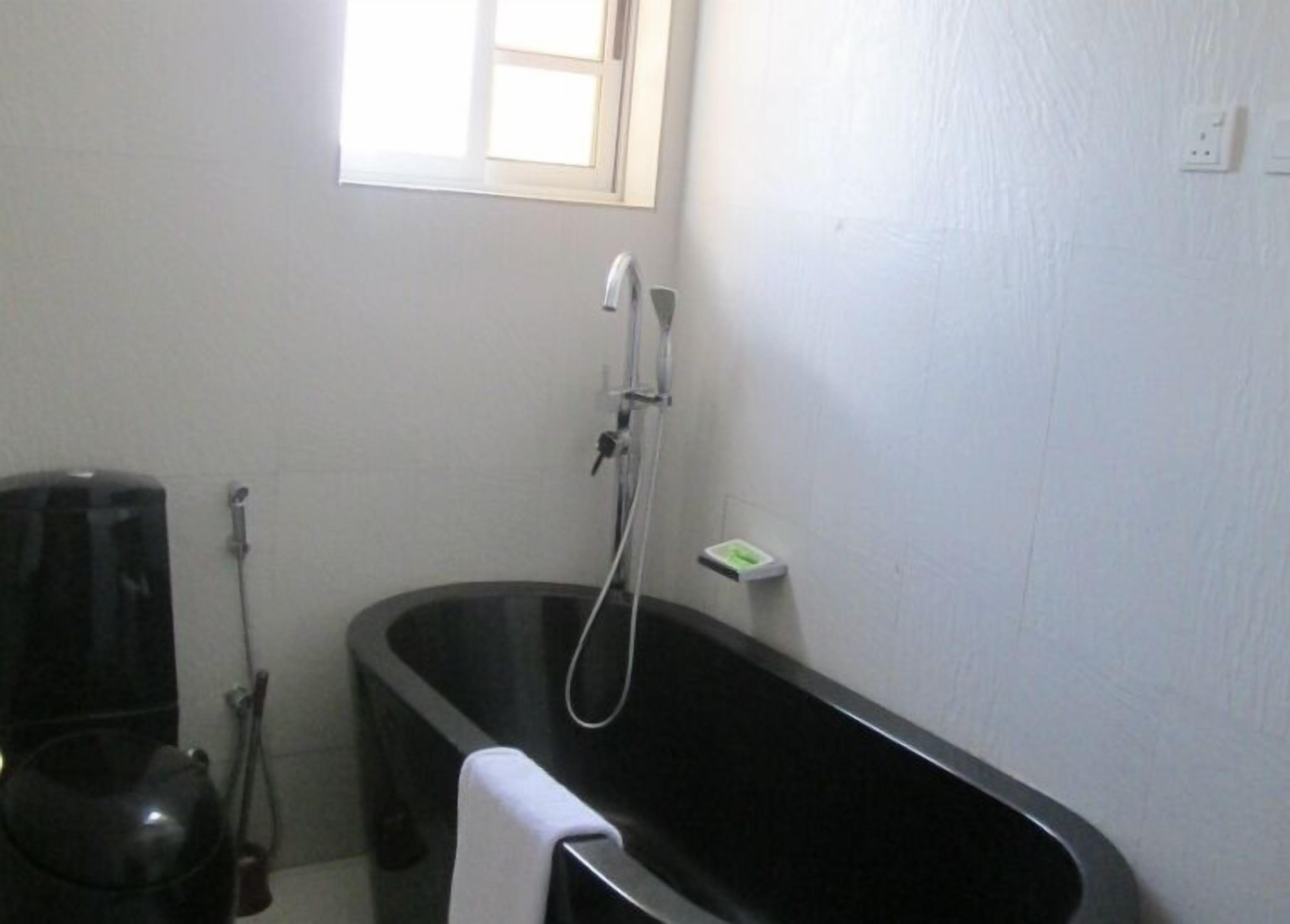 Ein Badezimmer mit einer schwarzen Badewanne, einem Fenster und einem Handtuchhalter.