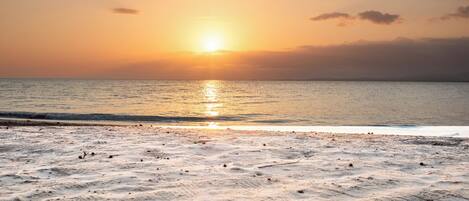 A beach with a sunset over the ocean.