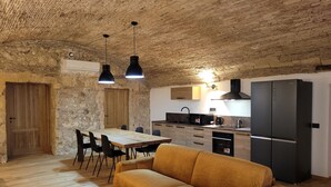A rustic kitchen with a wooden table, black chairs, a sofa, and a black refrigerator. - LUXURY DIMORA CANELLES (Cagliari)