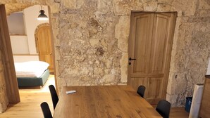 A wooden dining table with black chairs in a room with stone walls and a wooden door. - LUXURY DIMORA CANELLES (Cagliari)