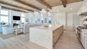 A spacious kitchen with a large island, wooden beams on the ceiling, pendant lights, and a modern design. - Loaded 30A Luxury Home! Steps to Beach! LSV, Bikes! Sleeps 22! (Santa Rosa Beach)