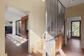 Staircase leads to an upper level, flanked by paneling and a mesh screen.