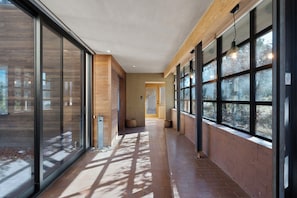 Contemporary corridor with glass and wood paneling, leading to an entrance.