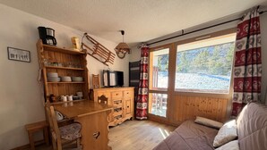 Et hyggeligt værelse med skrivebord i træ, fjernsyn og sofa.