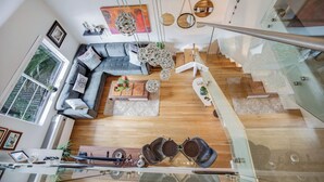 Una sala de estar moderna con un sofá gris, una mesa de centro y una escalera que lleva a un nivel superior.