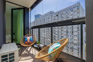A balcony with wicker chairs, a small table, and a white heater.
