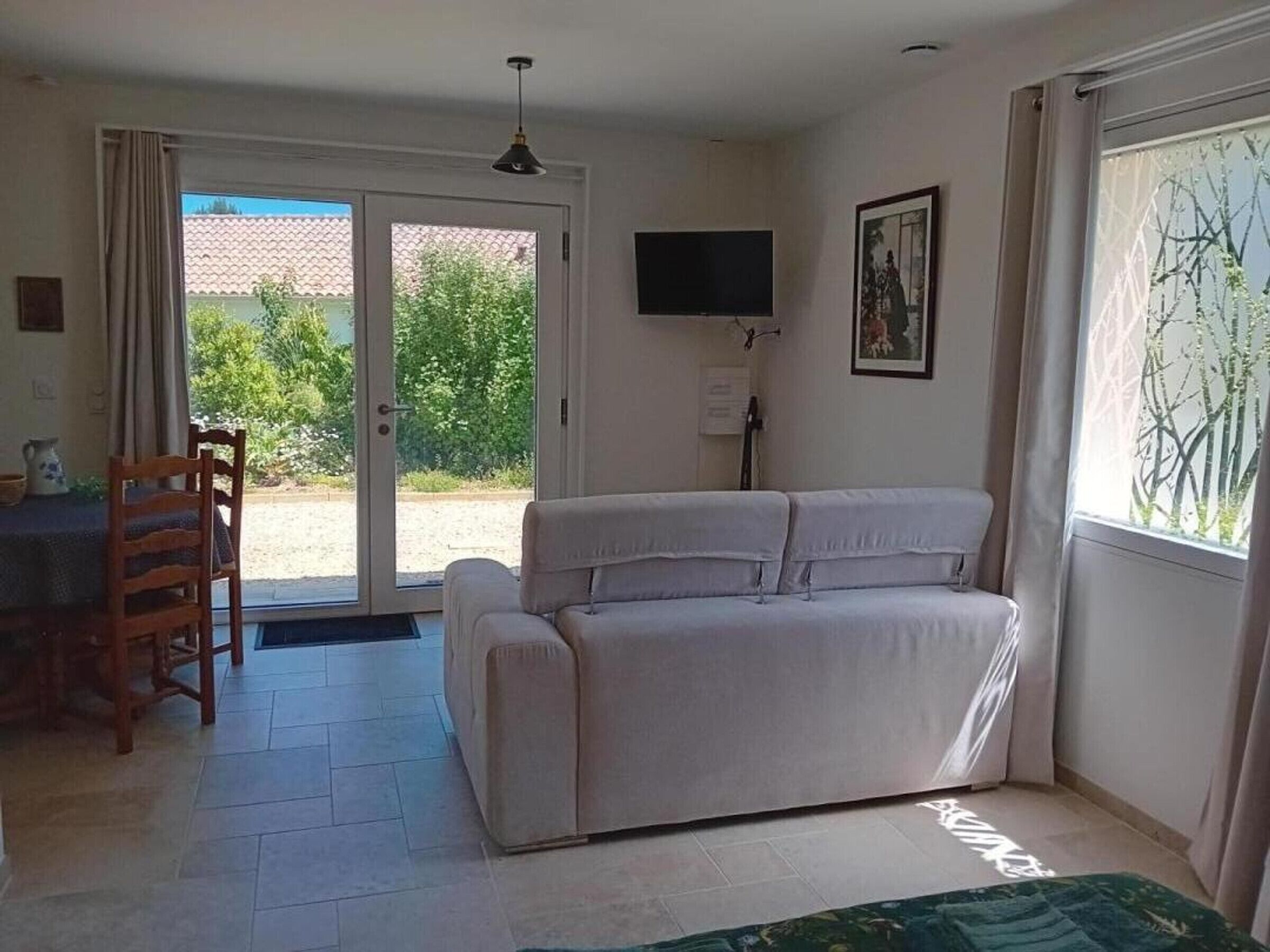 Een kamer met een bank, een televisie en een deur naar een buitenruimte.