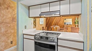 A modern kitchen with a gas stove, white cabinets, and a wooden accent wall. - Sandy Beaches *Heated Pool* Pet Friendly (Destin)