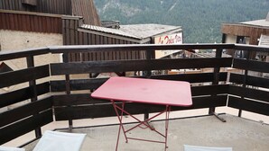A balcony with a red table and two white chairs, surrounded by a wooden railing. - Ski-in/ski-out studio, Les Orres 1650 center, 4 people (Les Orres)