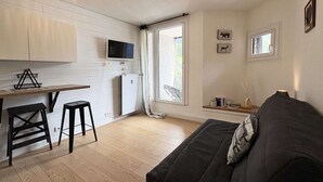 A compact living space with a kitchenette, a sofa, and a dining area.