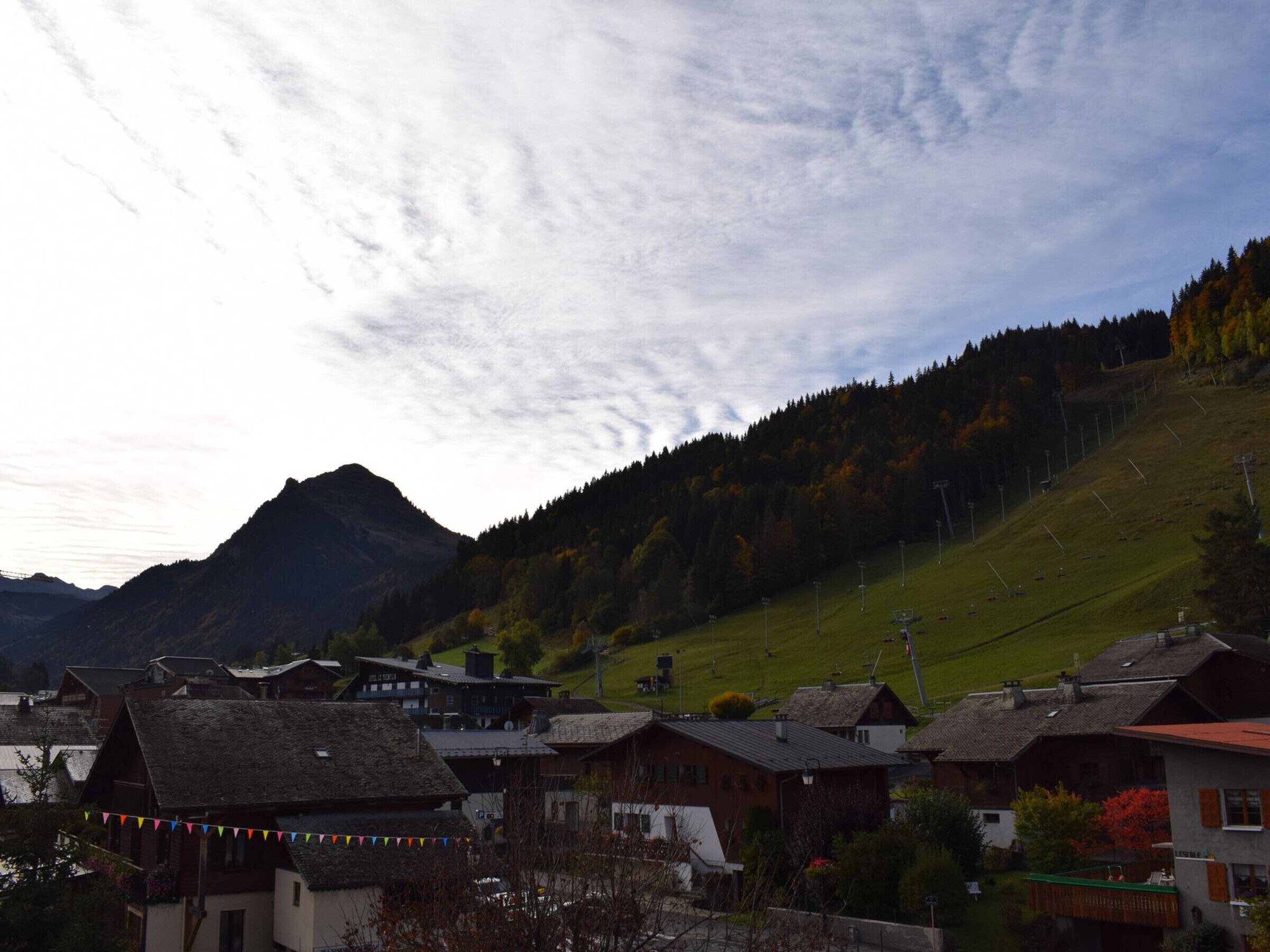 A village with traditional houses, a mountain in the background, and a clear sky.