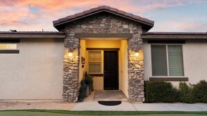 A house with a stone facade, a dark entrance door, and a small porch. - Desert Getaway- Private pool, access to PB & fitness centre! (Indio)