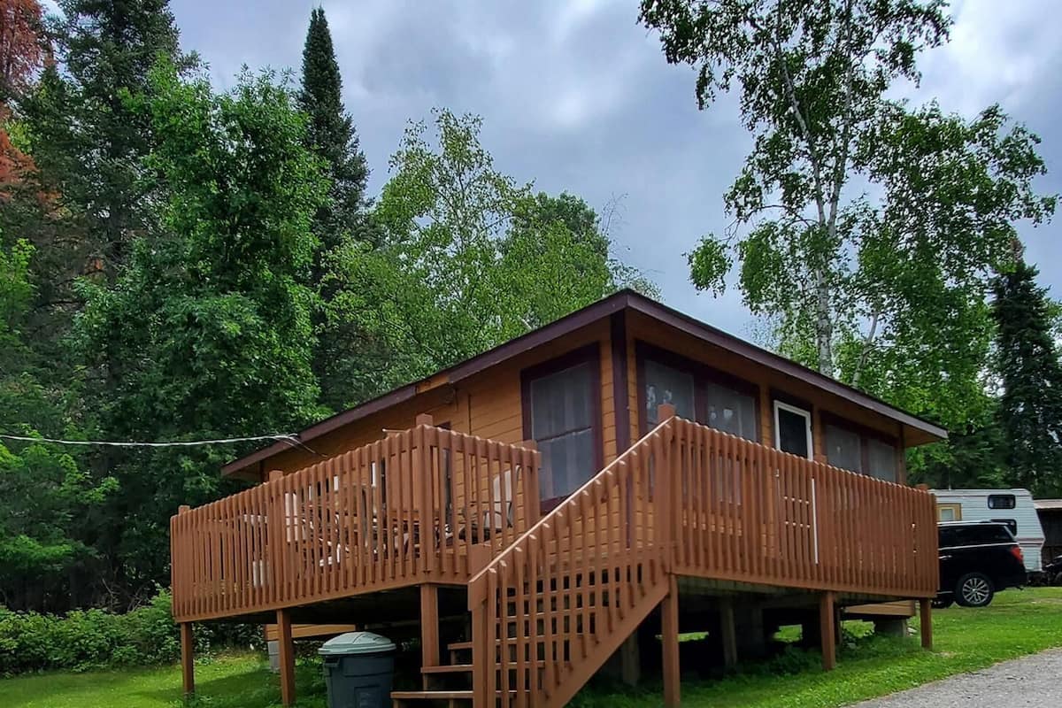 Une cabane en bois dotée d’une terrasse en bois et d’un escalier menant à l’entrée.