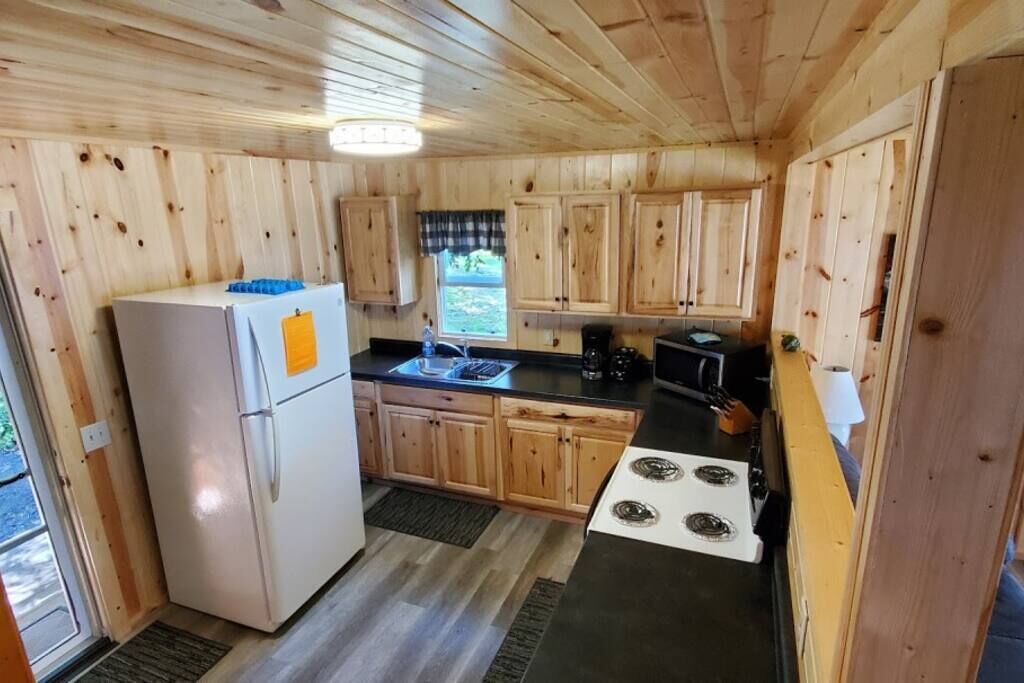 Une cuisine de taille réduite, dotée de meubles de rangement en bois, d’un réfrigérateur, d’une cuisinière et d’un évier.