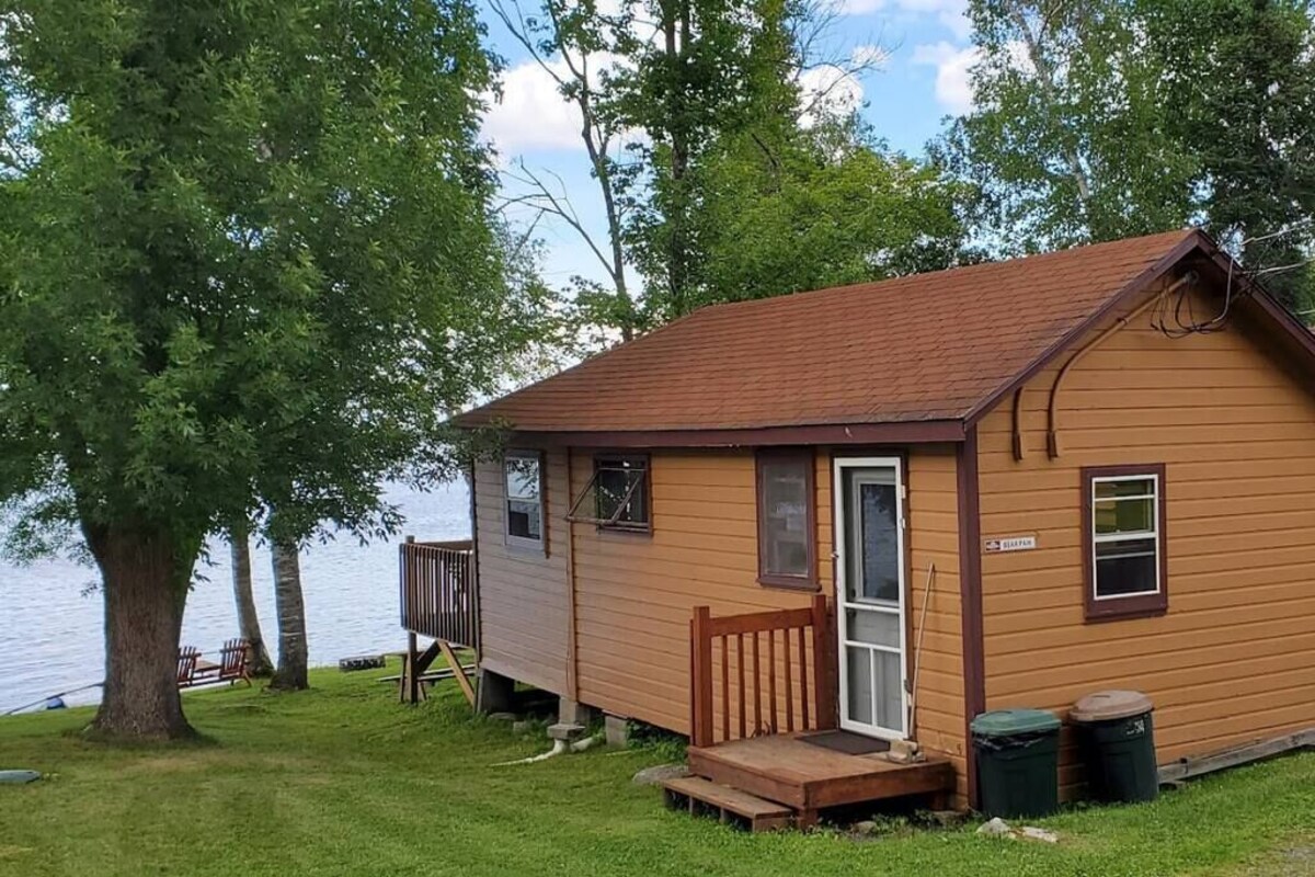 Une petite cabane en bois avec une véranda, une porte et une fenêtre.