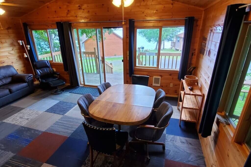 Eine Holzhütte mit einem großen Esstisch und Stühlen, einer Couch und einem kleinen Tisch mit einem Korb.