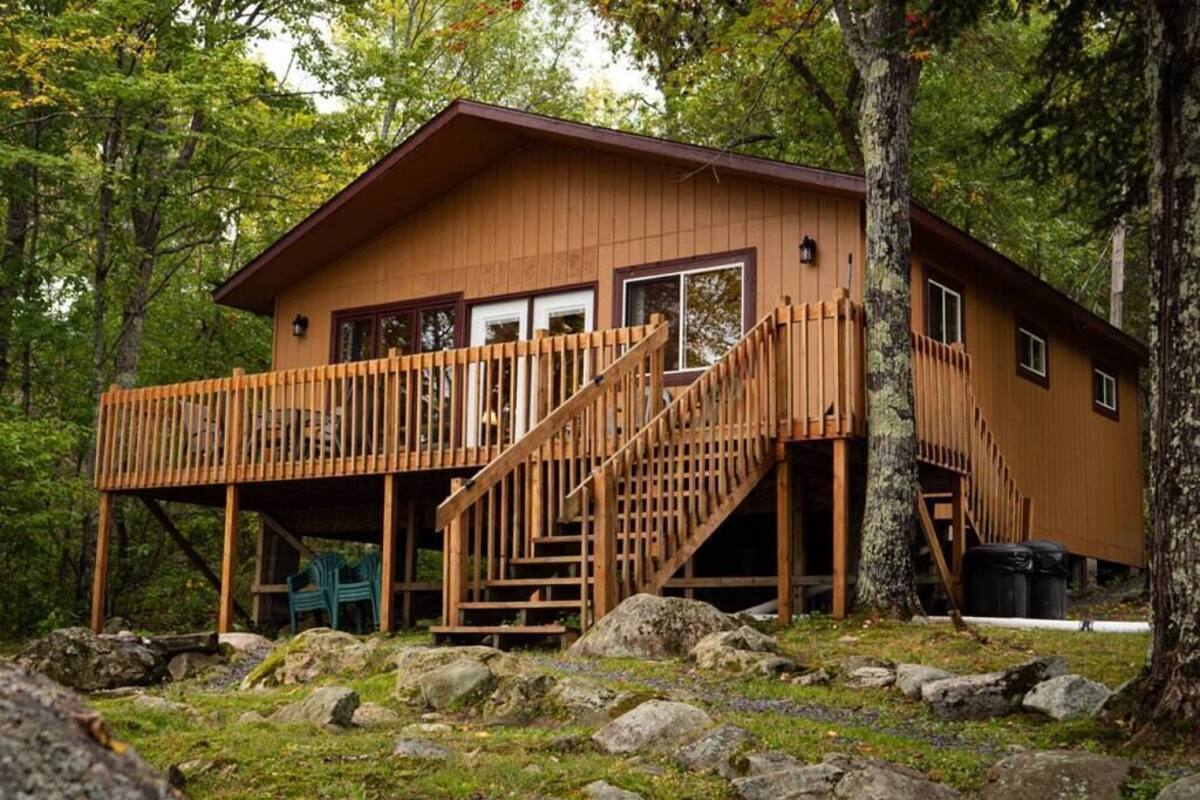 Une cabane dotée d’une terrasse en bois, d’un escalier et d’un porche.
