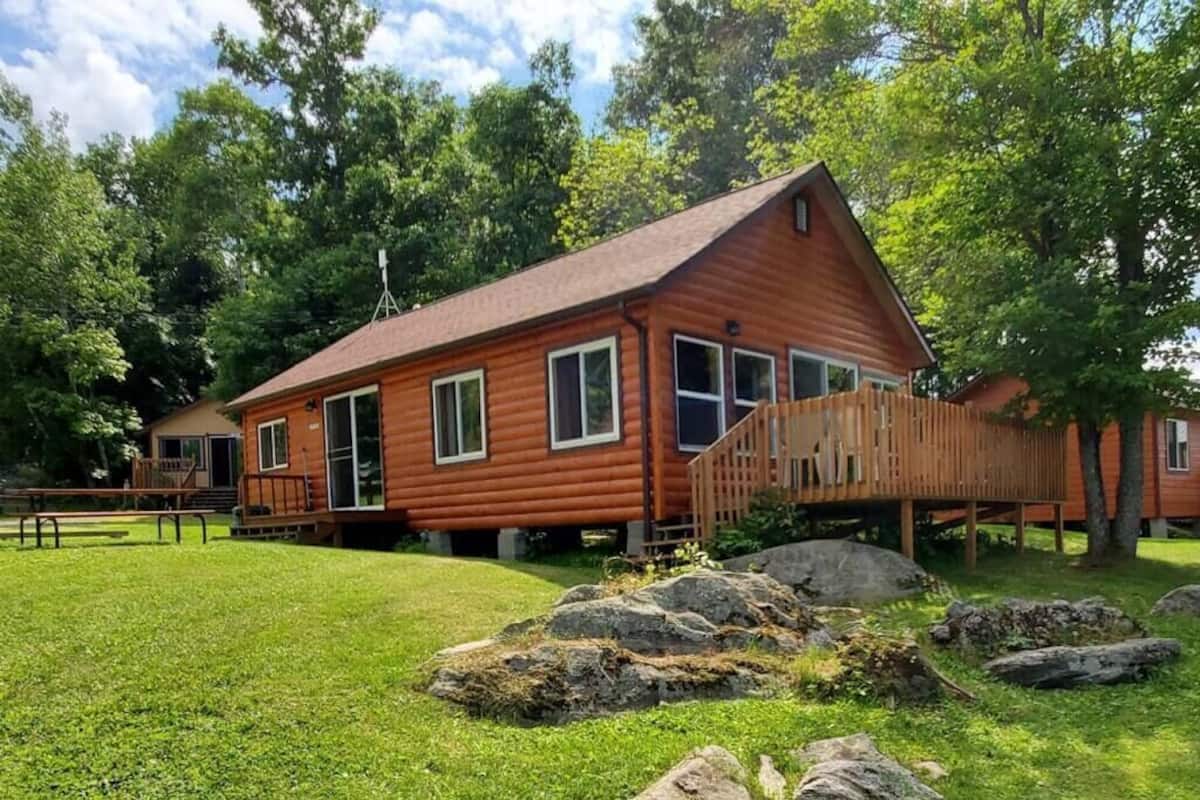 Une cabane en bois avec un toit en pente, de grandes fenêtres et une terrasse.