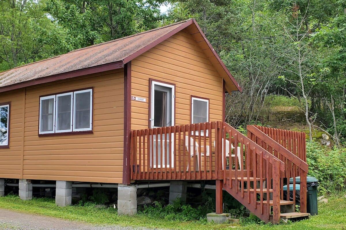 Une cabane en bois avec une véranda et un barbecue à l’extérieur.