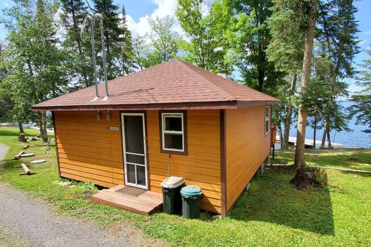 Une petite cabane en bois avec une porte, des fenêtres et un petit porche.
