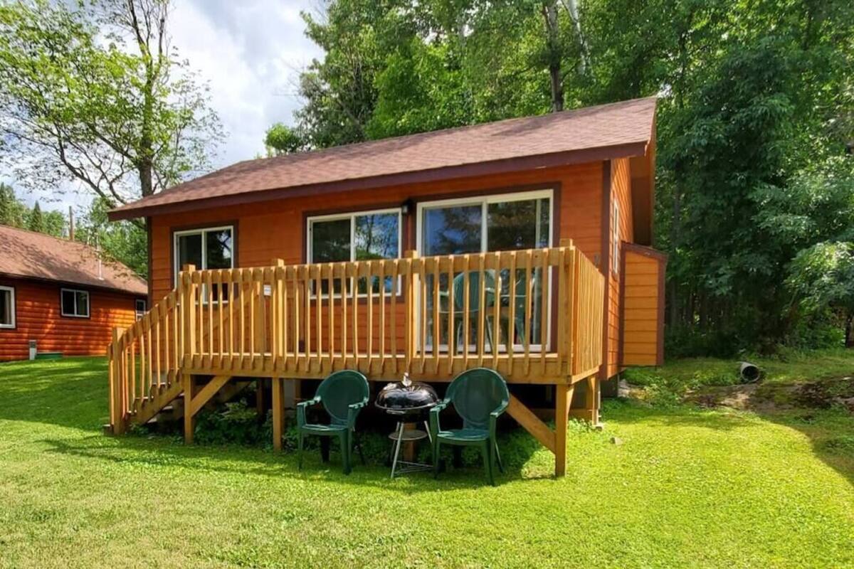 Une cabane en bois avec une terrasse, deux chaises et une petite table.