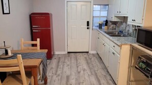 Cocina compacta con un refrigerador rojo, una mesa de comedor con sillas y un microondas.