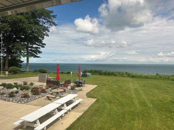 A patio with picnic tables, red umbrellas, and a view of the ocean. - House on Lake Erie Bluff! Gorgeous lakefront view with spectacular sunsets! (Lake City)