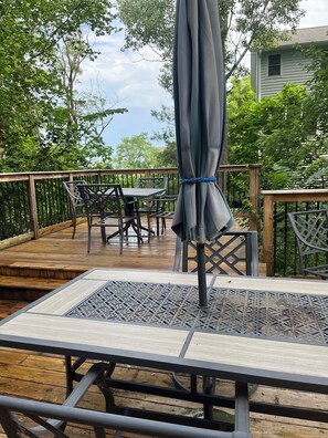 Una terraza de madera con una mesa, sillas, una sombrilla y barandilla.
