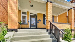 A two-story brick building with a covered front porch and a staircase leading to the entrance. - Dog-friendly Pittsburgh Home, 3 Mi to Downtown! (Pittsburgh)