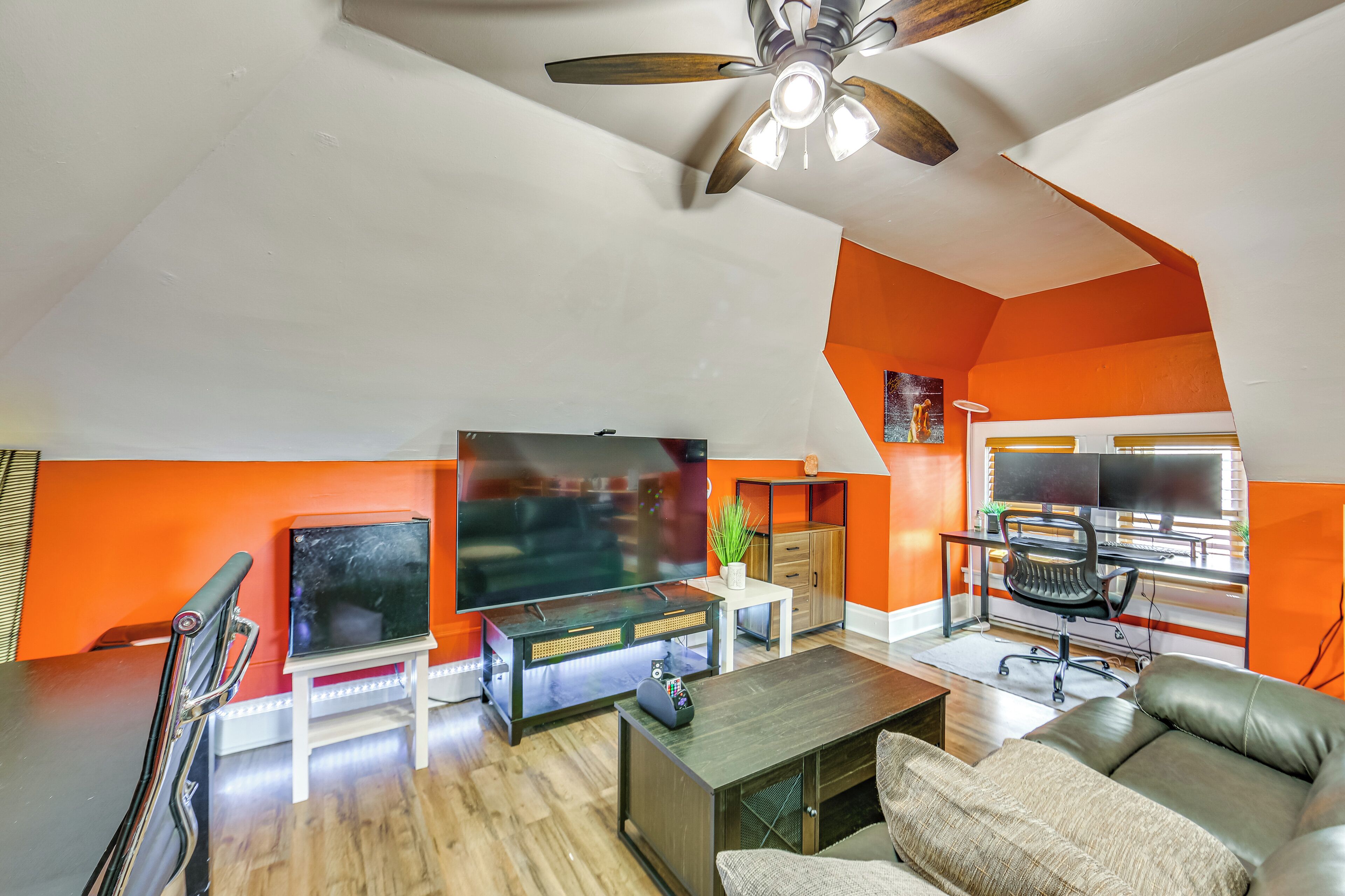A modern living room with a flat-screen TV, a ceiling fan, a sofa, and a coffee table.