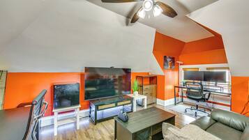 A modern living room with a flat-screen TV, a ceiling fan, a sofa, and a coffee table.