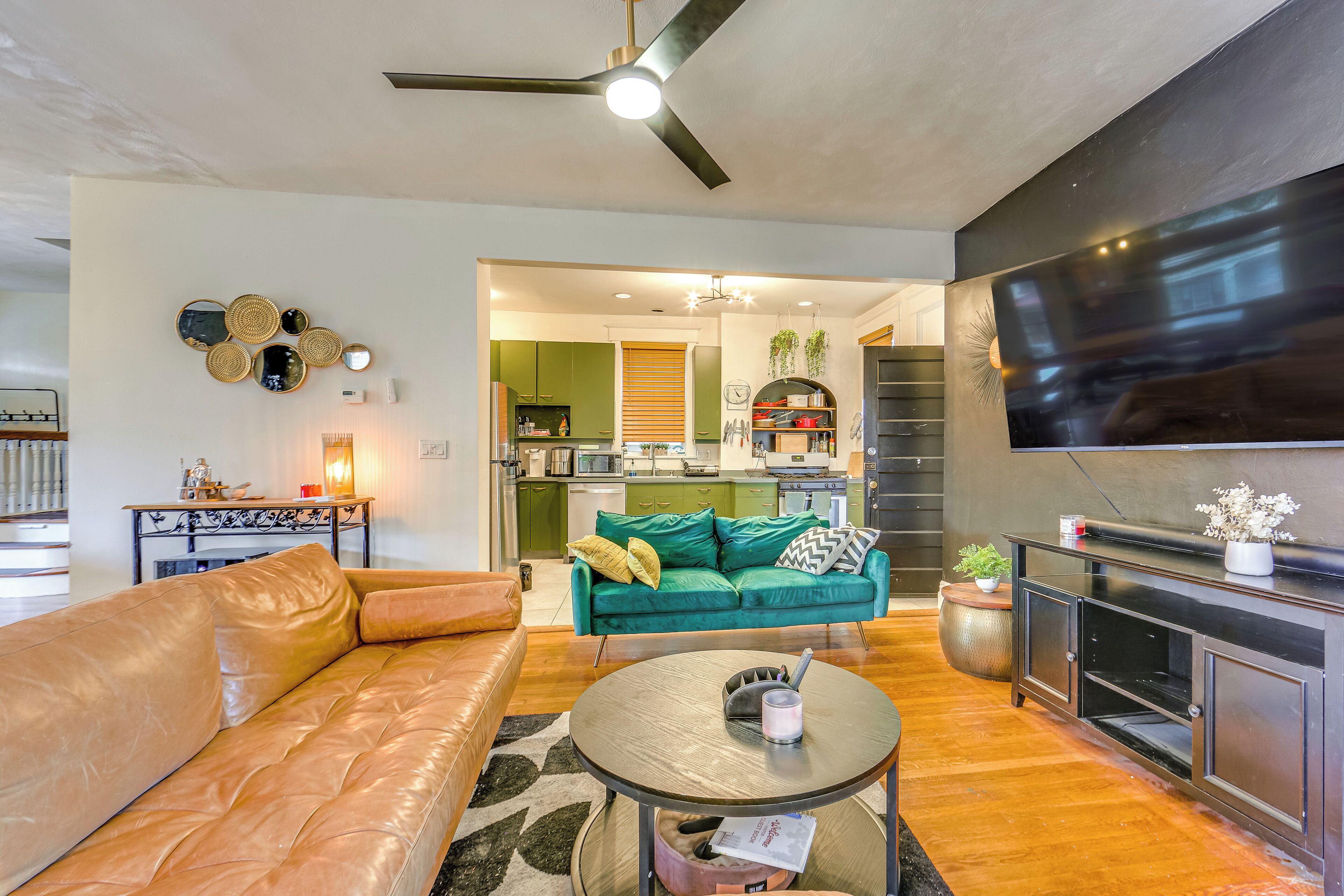 Una sala de estar moderna con un sofá de cuero, una mesa redonda para café y un televisor montado en la pared.