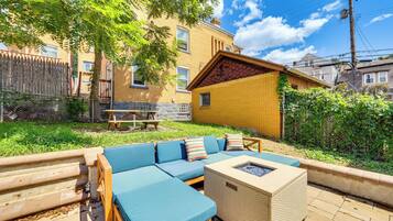 A patio area with a sofa set, a fire pit, and a wooden table.