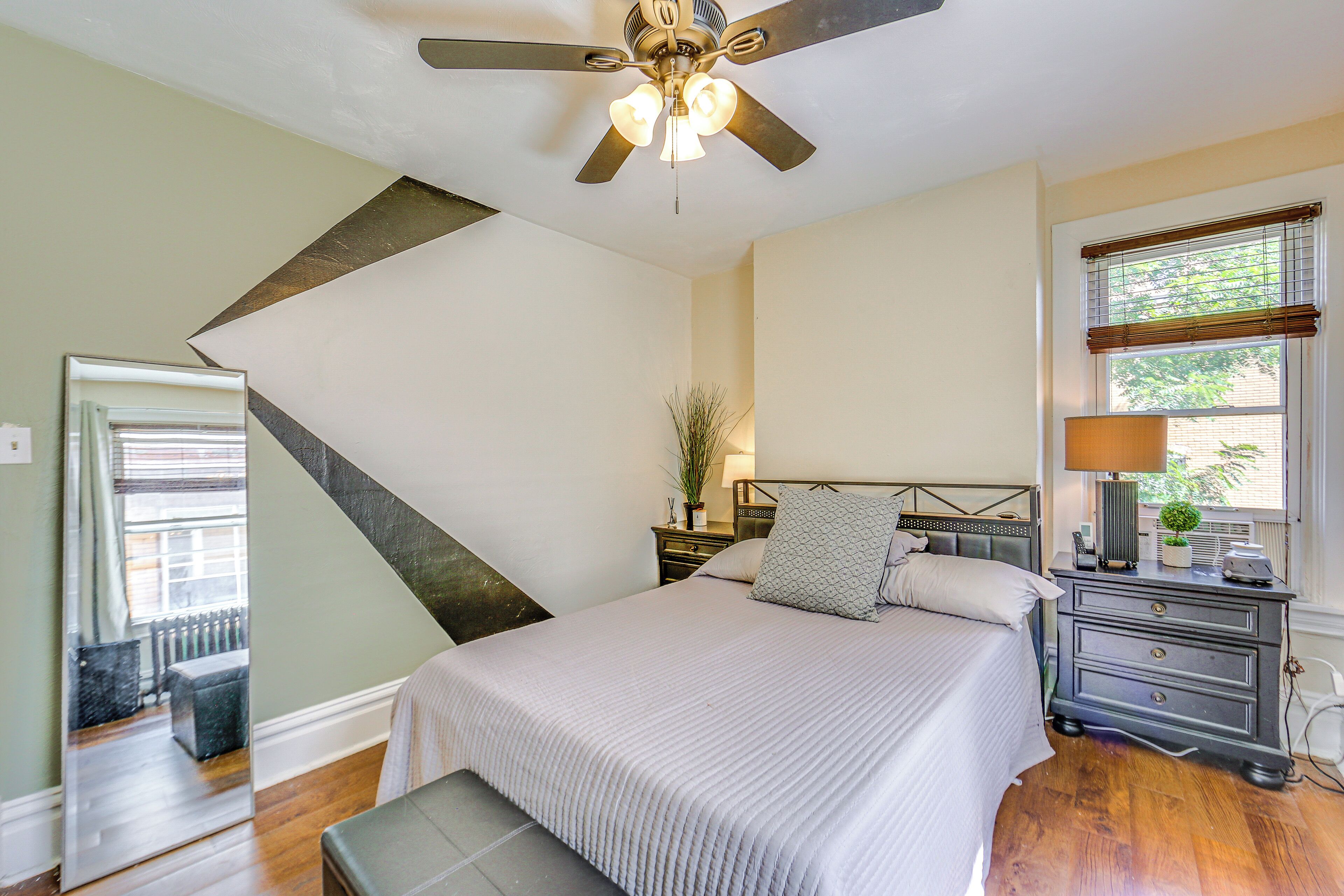 A bedroom with a bed, bedside table, lamp, and a ceiling fan.