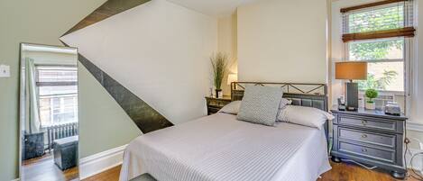 A bedroom with a bed, bedside table, lamp, and a ceiling fan.
