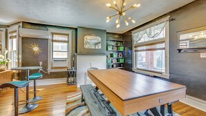 A dining area with a wooden table, bar stools, and a bench. There is a chandelier, a mirror, and a window with blinds. - Dog-friendly Pittsburgh Home, 3 Mi to Downtown! (Pittsburgh)