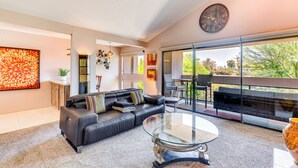 Un salon moderne avec une table basse en verre, un canapé en cuir et une grande fenêtre donnant sur un balcon.