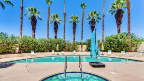 Une piscine à l’eau d’un bleu cristallin, entourée de palmiers et de chaises longues.