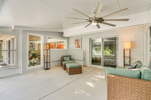 A covered patio area with a ceiling fan, wicker furniture, and a view through glass doors. - Walk to Beach: Cape Coral Home w/ Grill & Patio (Cape Coral)