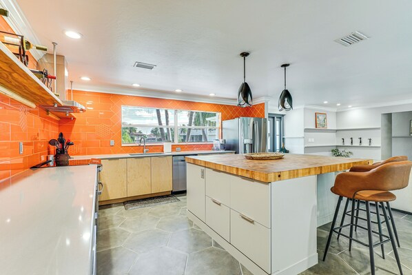 A modern kitchen with a central island, orange backsplash, and a view of the outdoors. - Walk to Beach: Cape Coral Home w/ Grill & Patio (Cape Coral)