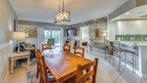 A spacious kitchen with a wooden dining table, bar stools, and a built-in island. - New Smyrna Beach Condo w/ Balcony & Ocean Walk (New Smyrna Beach)
